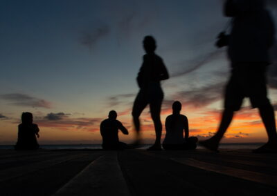 People in silhouette enjoy the dramatic sunset at the pier of Po